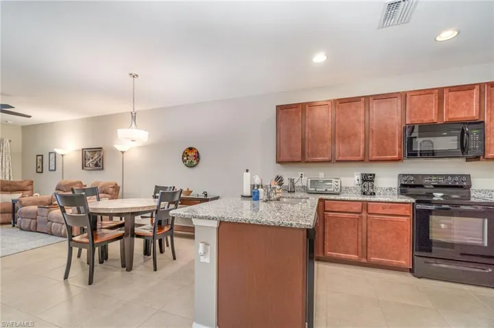 Kitchen with black & stainless appliances, recessed lights, sink, and granite countertops