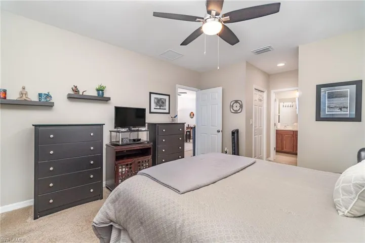Primary Bedroom with 2 walk-in closest, ceiling fan, light carpet, and ensuite bathroom