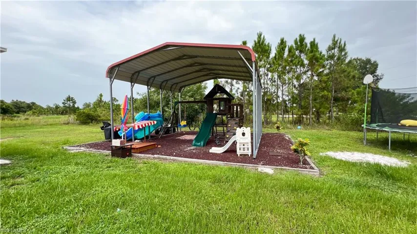 View of playground with a trampoline and a lawn