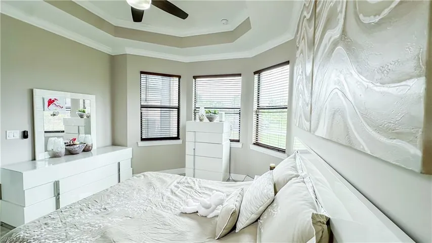Bedroom with ornamental molding, ceiling fan, and a raised ceiling