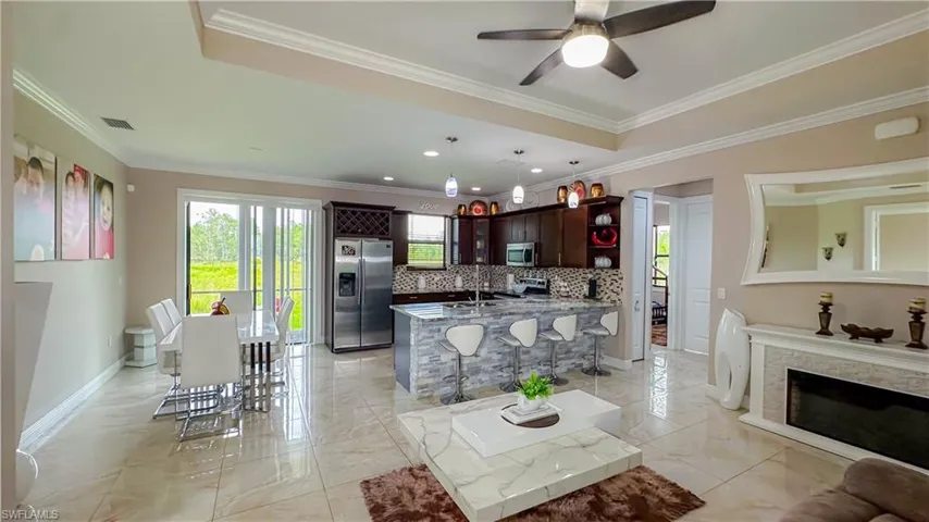 Tiled living room with a raised ceiling, ornamental molding, sink, and ceiling fan