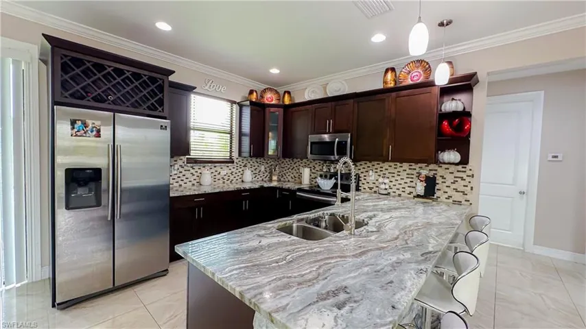 Kitchen with decorative backsplash, dark brown cabinetry, appliances with stainless steel finishes, and sink