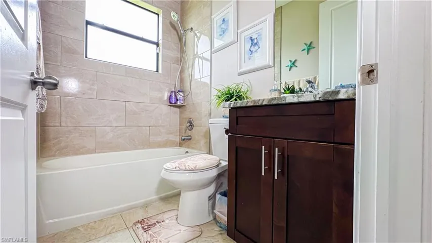 Full bathroom featuring vanity, tile patterned flooring, tiled shower / bath combo, and toilet