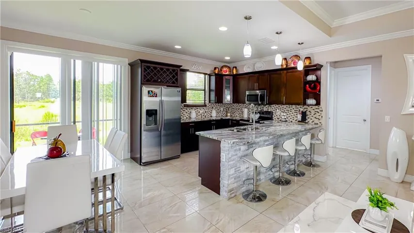 Kitchen with decorative light fixtures, light tile patterned flooring, stainless steel appliances, decorative backsplash, and crown molding