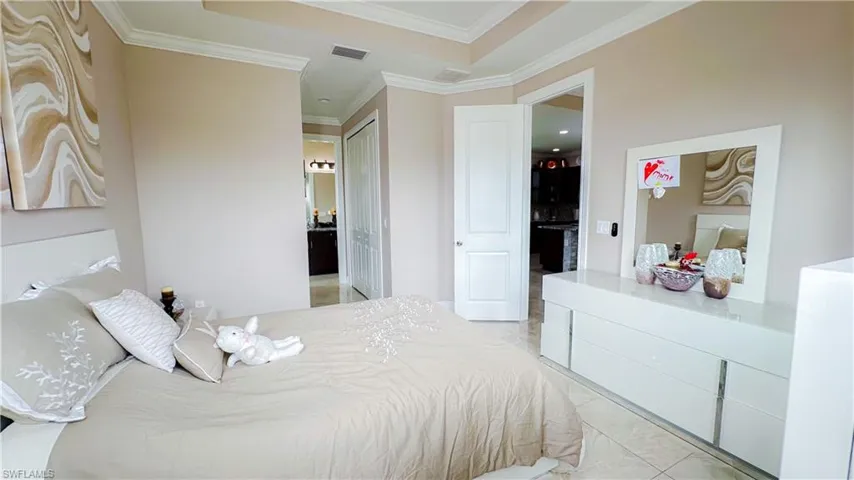 Bedroom featuring crown molding, a raised ceiling, and light tile patterned floors