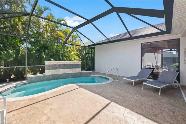 Screened pool enclosure featuring a custom-shaped pool with integrated spa and a decorative tiled water feature