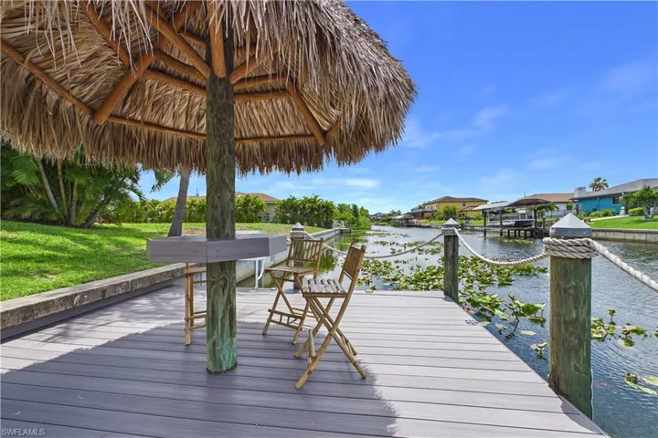 Waterfront composite decking with a built-in tiki hut featuring a thatched roof and bar-height counter