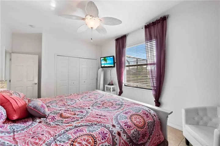 Bedroom featuring a ceiling fan, window with horizontal blinds, and a double-door closet with white bi-fold doors