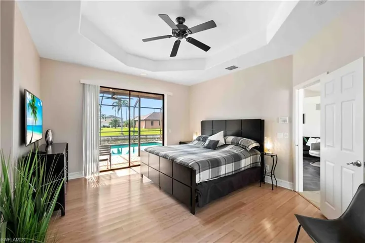 Master Bedroom featuring ceiling fan, light hardwood / wood-style flooring, access to outside, and a tray ceiling