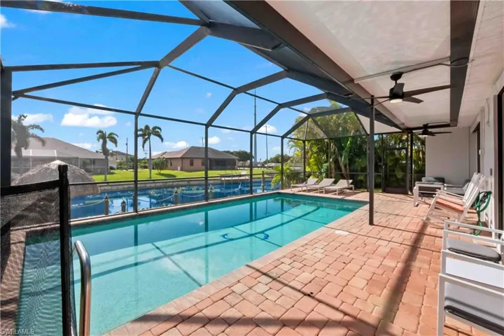 Screened lanai featuring a swimming pool, red brick paver decking, and a covered patio area with ceiling fans