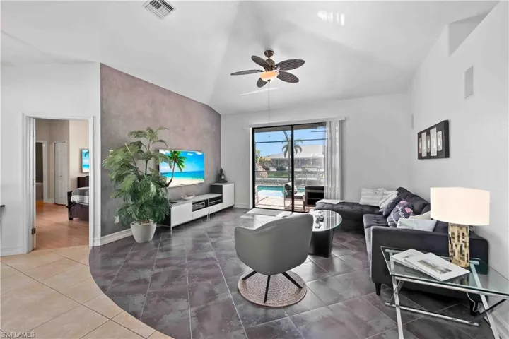 Living room with ceiling fan, tile patterned flooring, and lofted ceiling