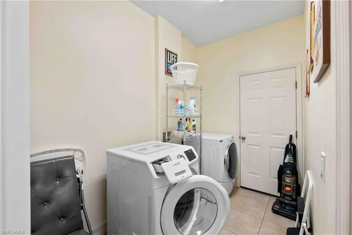 Washroom featuring light tile patterned floors and washing machine and dryer