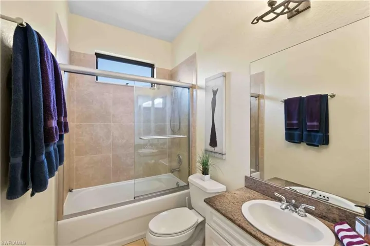 Full bathroom featuring toilet, vanity, and shower / bath combination with glass door