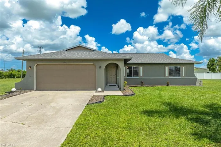 Ranch-style house featuring a garage and a front lawn