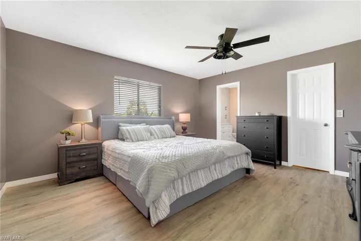 Bedroom featuring ensuite bath, light wood-type flooring, and ceiling fan