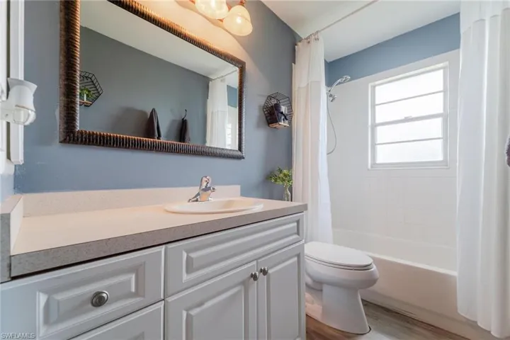 Full bathroom featuring vanity, wood-type flooring, toilet, and shower / tub combo with curtain