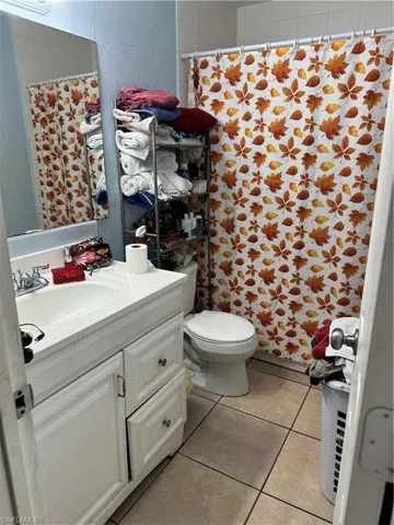 Bathroom with a shower with shower curtain, tile patterned floors, vanity, and toilet
