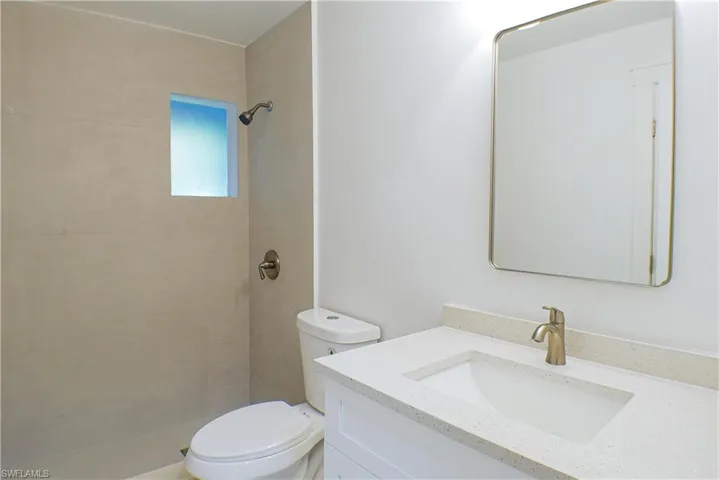 Bathroom featuring vanity, a tile shower, and toilet