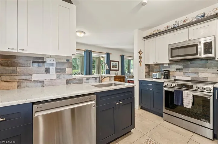 The kitchen features white custom cabinets, light tile patterned floors, gorgeous counter tops, tile back splash, and stainless steel appliances