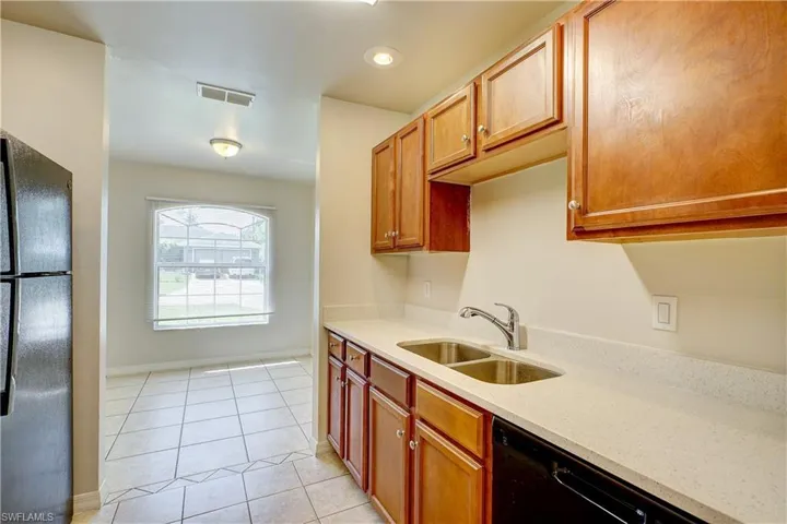 Kitchen with light tile patterned floors, sink, and black appliances