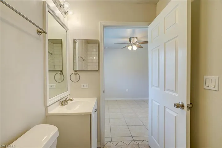Bathroom with tile patterned floors, ceiling fan, vanity, and toilet