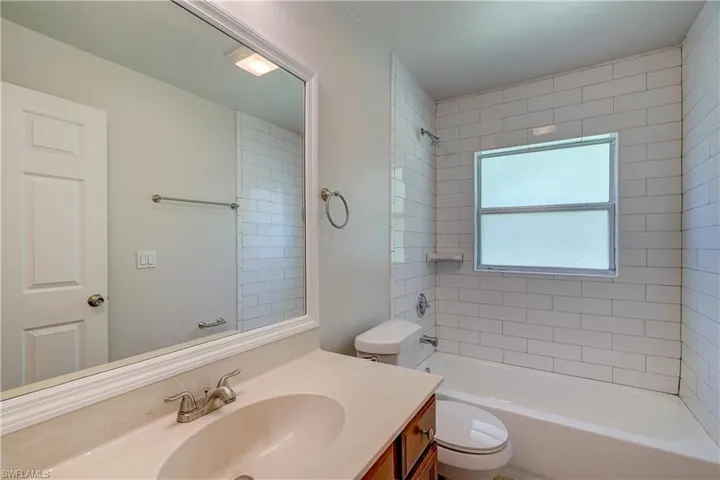 Full bathroom with tiled shower / bath, vanity, and toilet