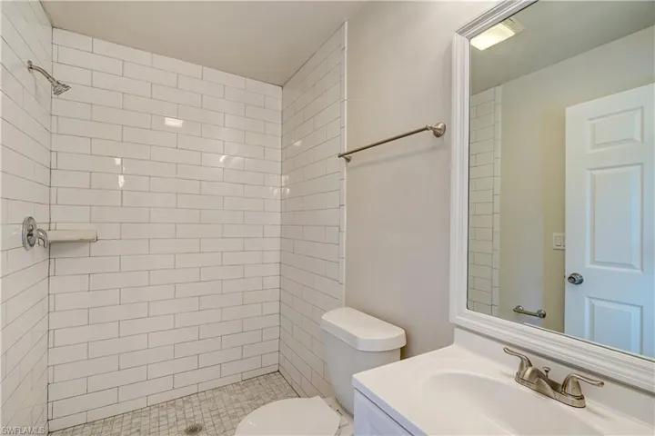 Bathroom with a tile shower, vanity, and toilet