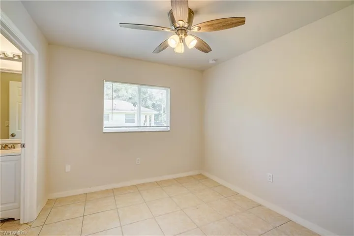 Empty room featuring ceiling fan, light tile patterned floors, and sink
