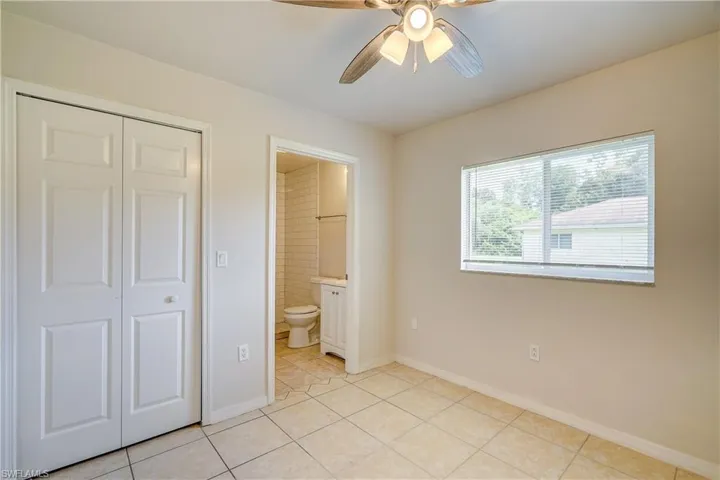 Unfurnished bedroom with a closet, ceiling fan, light tile patterned flooring, and connected bathroom