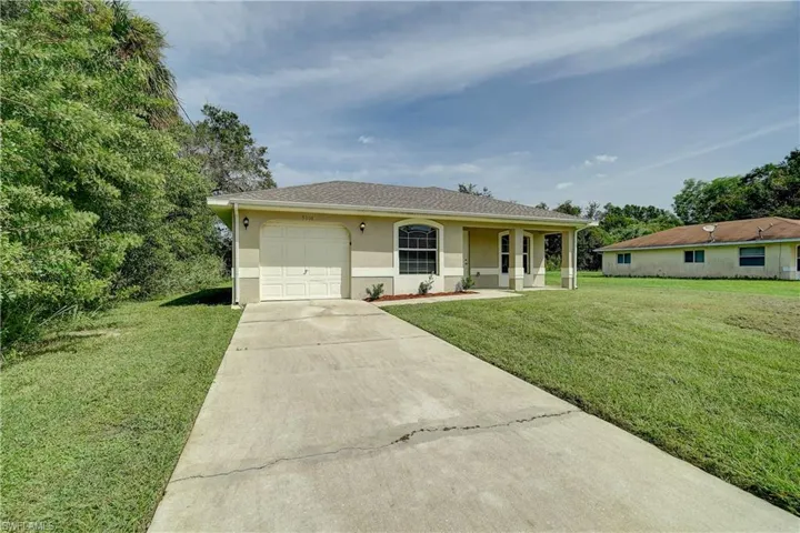 Single story home featuring a garage, a front lawn, and covered porch