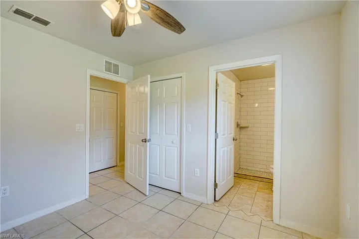 Unfurnished bedroom featuring light tile patterned floors, ceiling fan, and ensuite bathroom