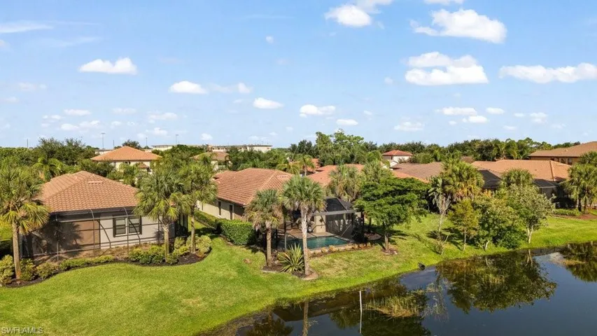 Aerial perspective showcasing a community of homes with tile roofs, lush landscaping, and private pools