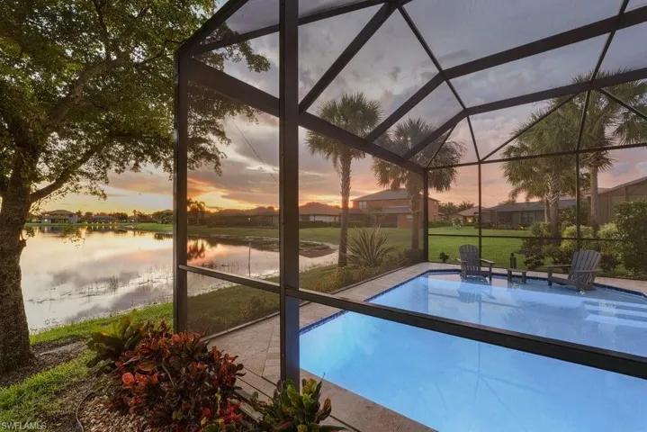 Screened-in outdoor pool with paver decking, overlooking a tranquil lake