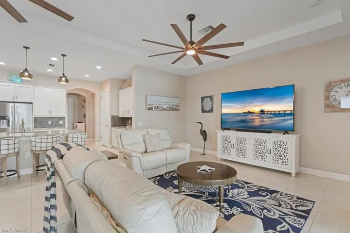 Open concept living area featuring recessed lighting, a tray ceiling, and tile flooring