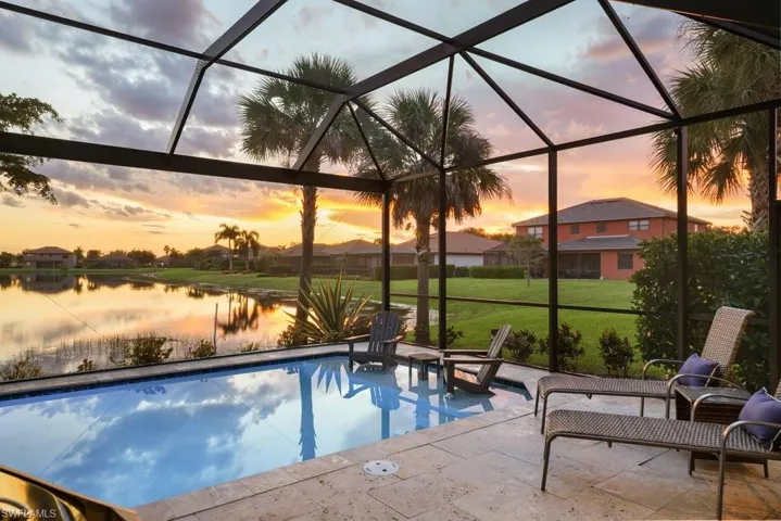 Screened lanai featuring a swimming pool, stone tile decking, and a lake backdrop
