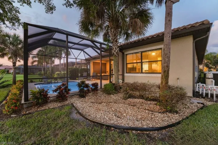 Screened pool enclosure featuring an in-ground pool, covered patio, and tiled roof