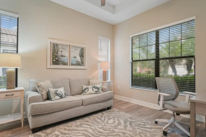 Tray ceiling, recessed lighting, wood-finish flooring, two large windows with blinds, and neutral wall tones