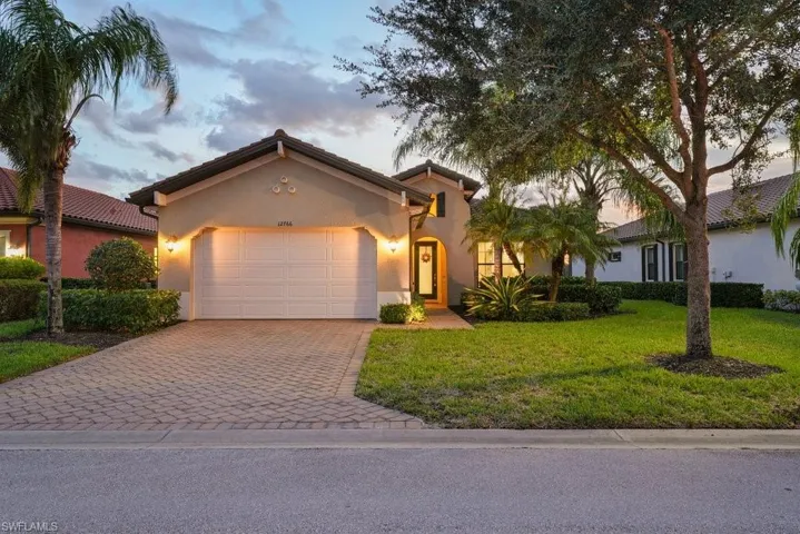 Paver driveway and walkway, stucco exterior, arched entry, tile roof, and landscaped grounds