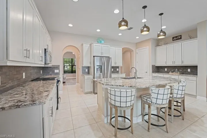 Kitchen featuring light-toned cabinetry, granite countertops, tile flooring, stainless steel appliances, and recessed lighting