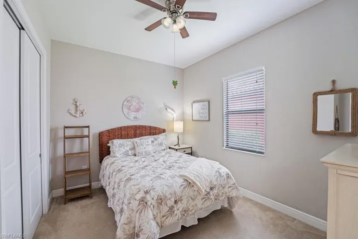 Neutral tone wall paint, carpeted flooring, window with blinds, and white bi-fold closet doors