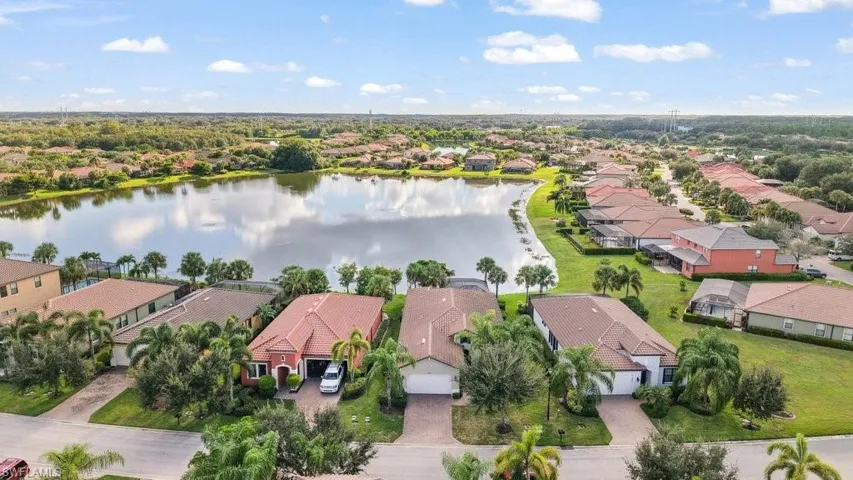Aerial perspective of a developed residential area featuring multiple single-family homes, a substantial body of water, and surrounding green spaces
