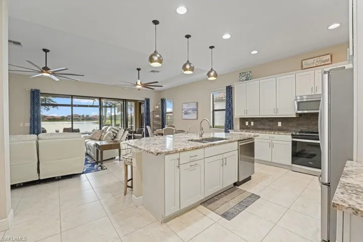 Open-concept kitchen featuring an island with a stainless steel sink, light-toned cabinetry, and integrated stainless steel appliances