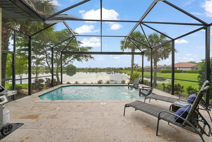 Screened outdoor living area featuring a swimming pool, stone-finish patio, and water frontage