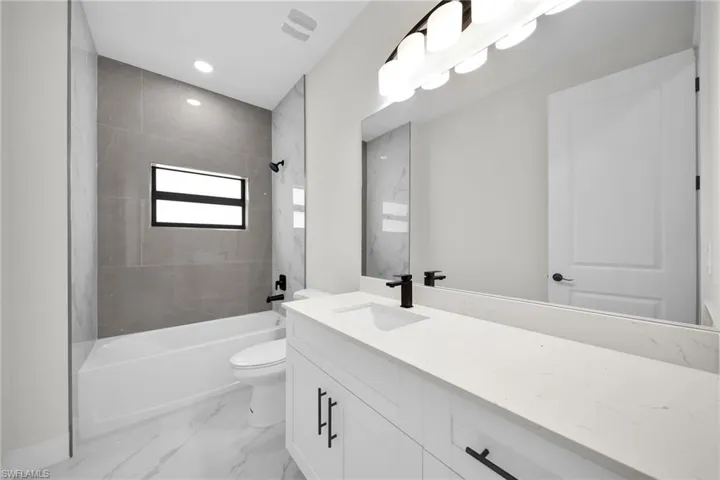 Full bathroom with tiled shower / bath, toilet, and vanity