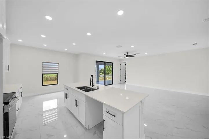 Kitchen with ceiling fan, a wealth of natural light, an island with sink, and sink