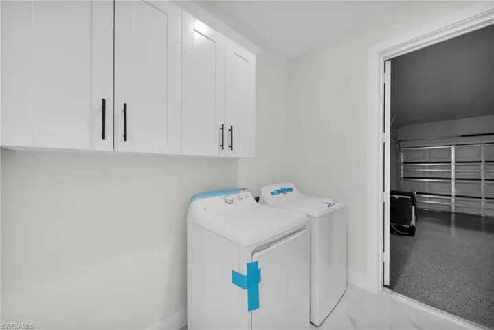 Clothes washing area featuring washer and dryer and cabinets