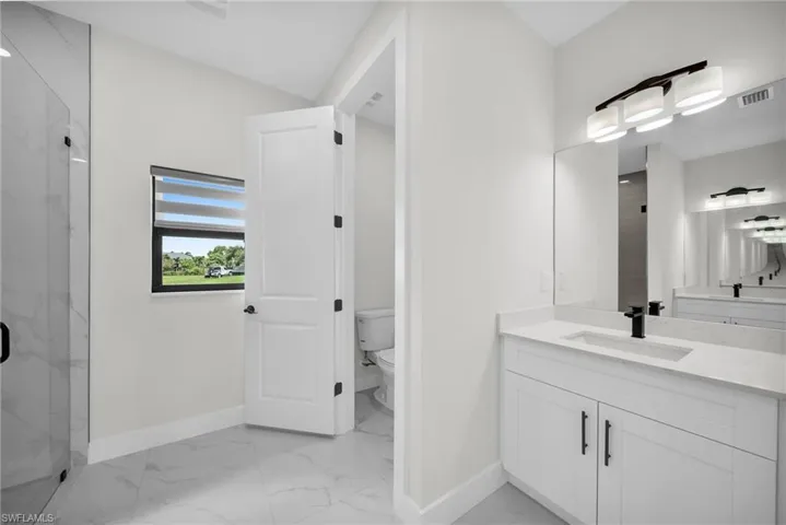 Bathroom with vanity, toilet, and an enclosed shower