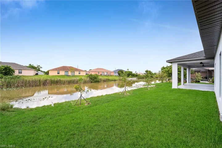 View of yard with a water view, ceiling fan, and a patio area