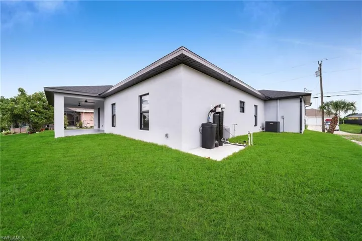 Back of house with central air condition unit, ceiling fan, a lawn, and a patio area