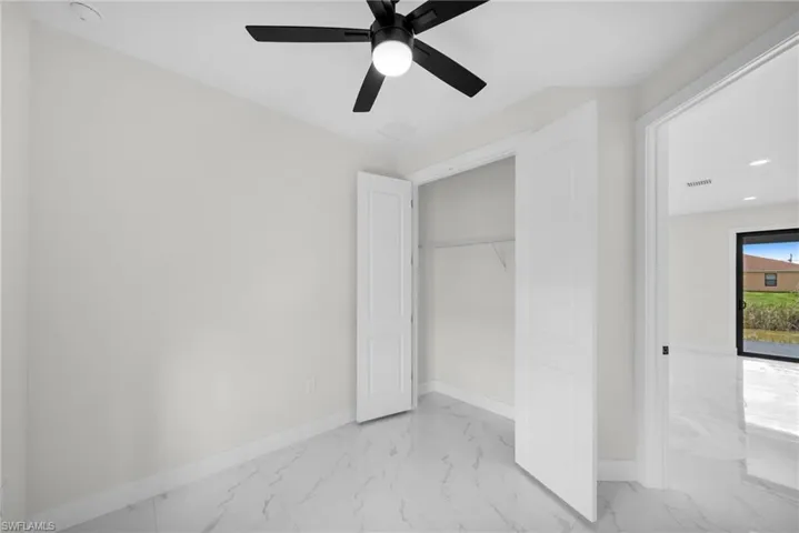Unfurnished bedroom with ceiling fan and a closet